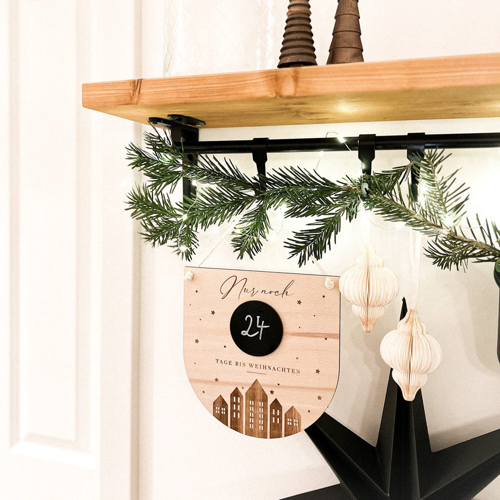 Weihnachtscountdown Holzschild neben weihnachtlicher Dekoration.