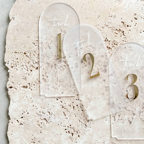 Nahaufnahme der satinierten Tischnummern mit spiegelgoldenen 3D-Zahlen und feinem UV-Druck Tisch auf Travertinhintergrund