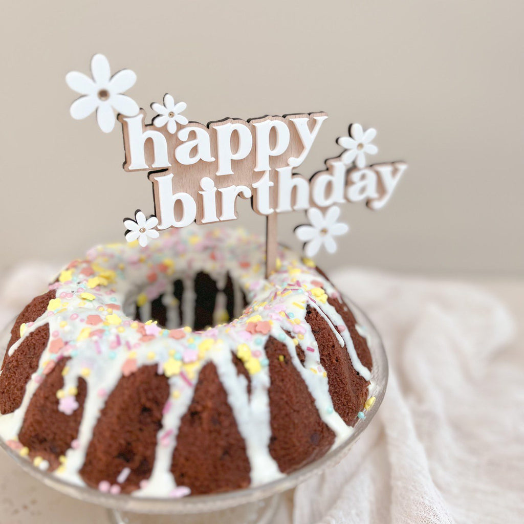 Kinder beobachten gespannt, wie der 'Happy Birthday' Cake Topper aus Holz seinen Platz auf dem Geburtstagskuchen findet