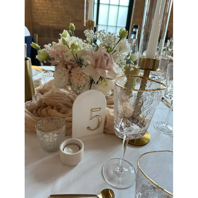 Tischnummer 5 in weißem Bogen-Acryl mit goldener 3D-Zahl auf gedecktem Hochzeitstisch mit Blumen und Kerzenständern