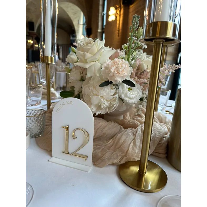 Tischnummer 12 in weißem Bogen-Acryl mit goldener 3D-Zahl neben goldenen Kerzenständern und weißen Rosen