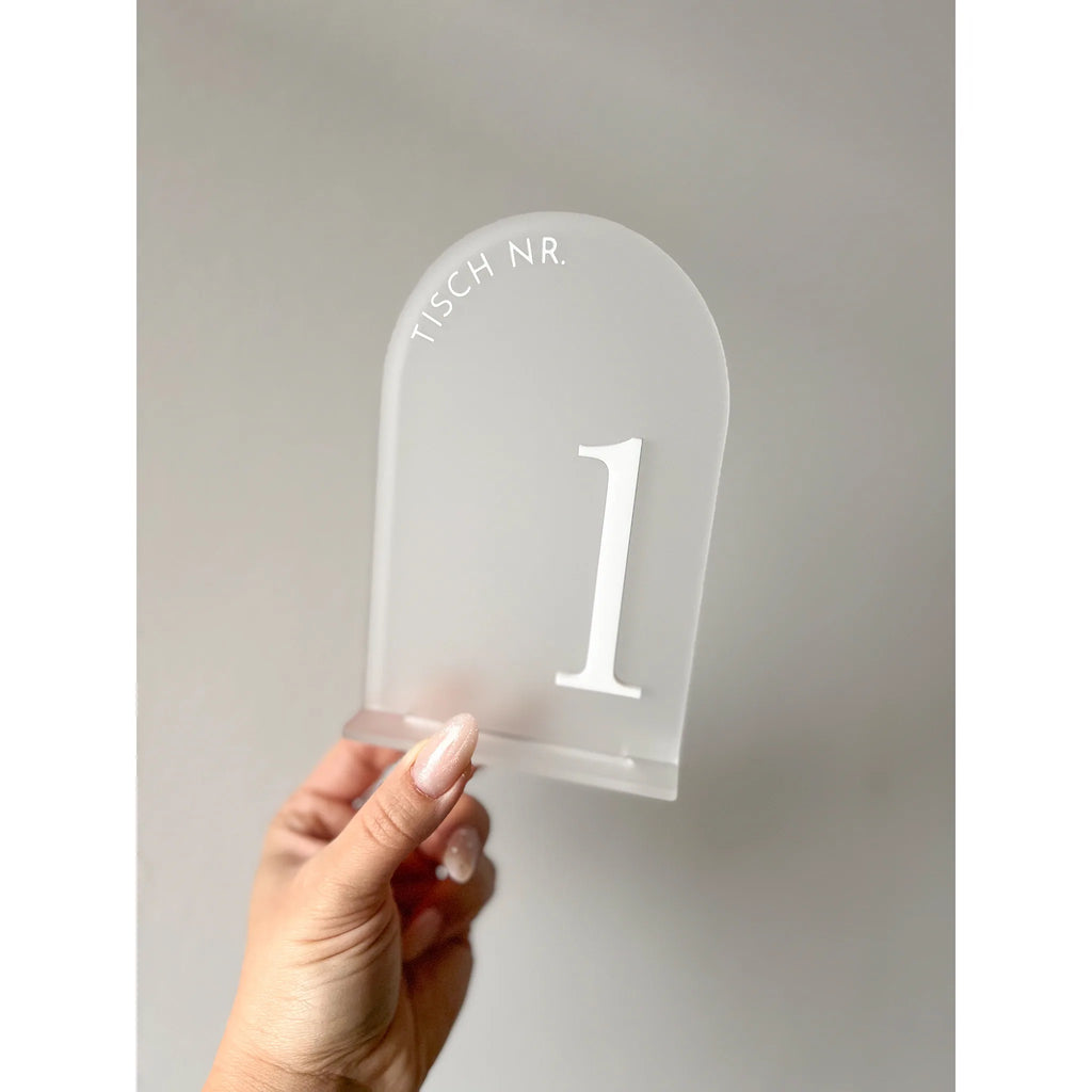 Hand hält transparente Tischnummer in Bogenform mit weißer 3D-Zahl 1 und Schriftzug Tisch Nr.
