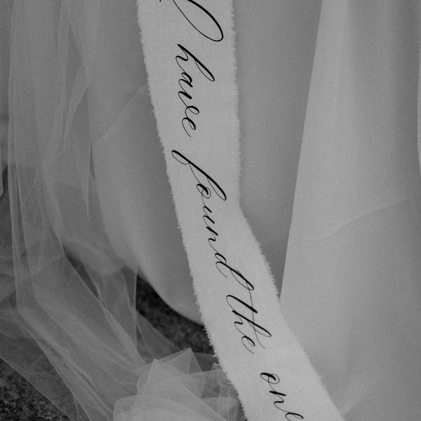 Stoffbanner mit Liebesspruch, halb verdeckt von fließendem Tüll, Detailaufnahme in Schwarz-Weiß