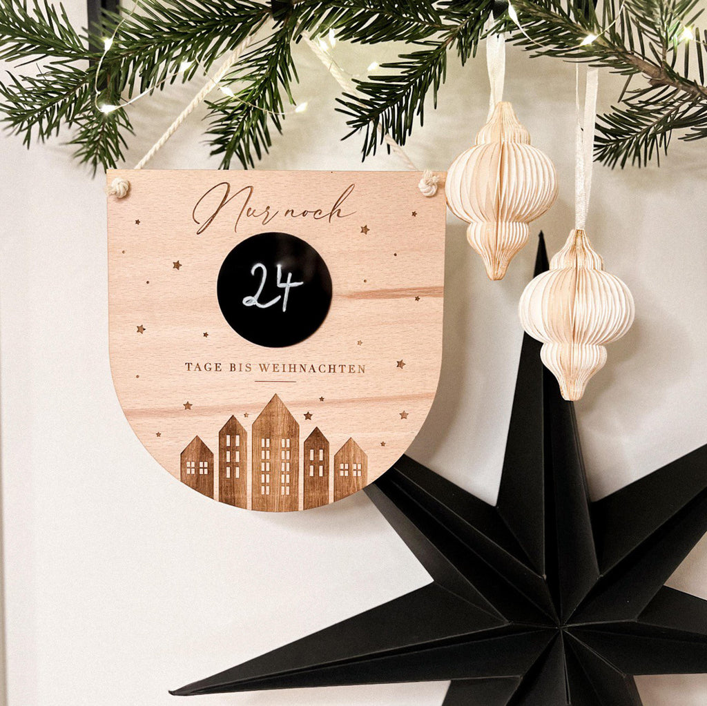 Kind schreibt auf Weihnachtscountdown Holzschild in Kinderzimmer.