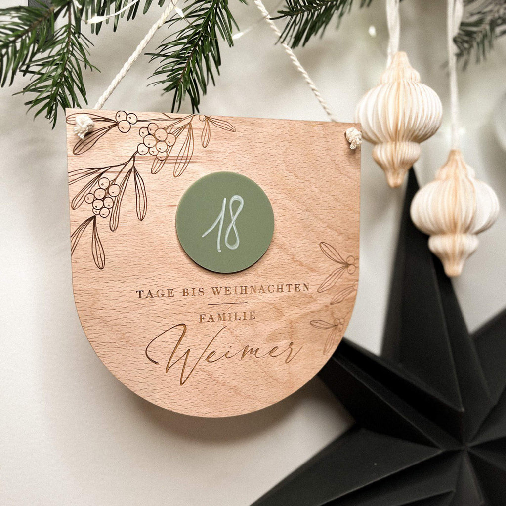 Kind schreibt auf Weihnachtscountdown Holzschild in Kinderzimmer.