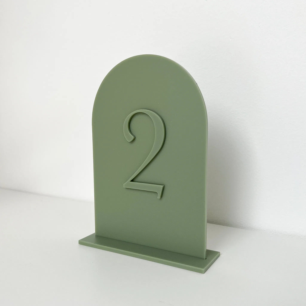 Tischnummer aus Acryl in Bogenform mit Ton-in-Ton-Zahl 2 und Acrylfuß, seitliche Ansicht vor weißem Hintergrund.