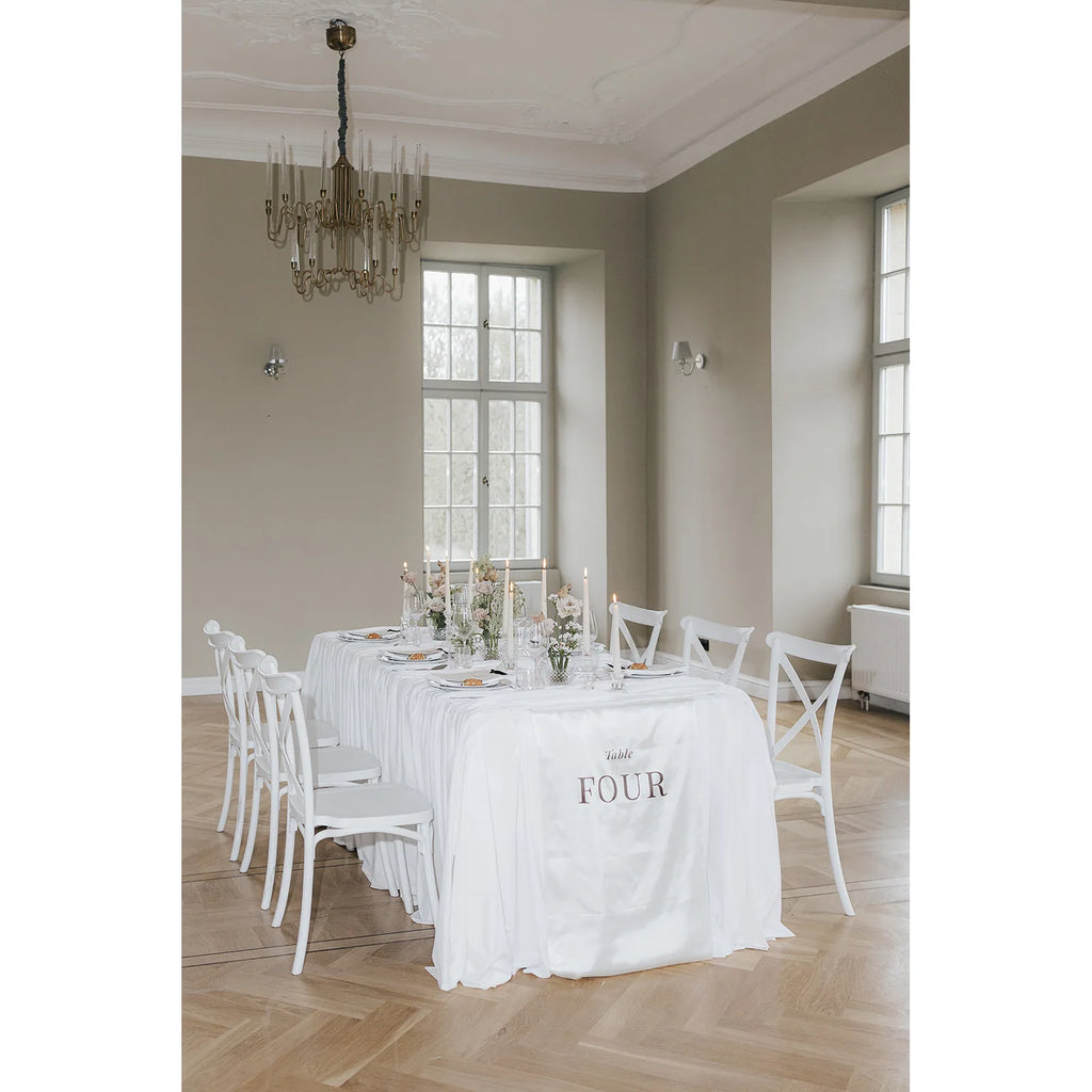 Seitliche Ansicht des gedeckten Tisches mit Blumendeko, Kerzen und herabhängendem Stoffbanner mit der Aufschrift Table Four