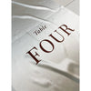 Nahaufnahme des Satinstoffs mit gedrucktem Schriftzug Table Four in warmem Braunton