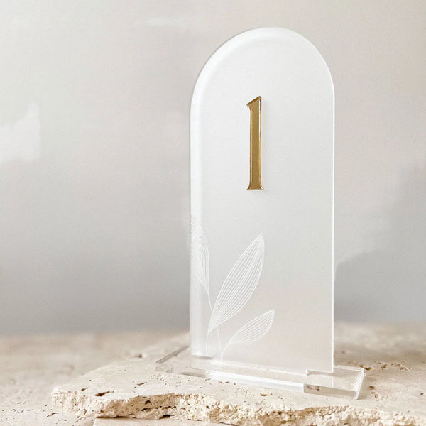 Freigestellte Tischnummer aus Acrylglas in Bogenform mit goldener 3D-Zahl 1 und filigraner Blattgravur