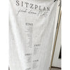 Nahaufnahme des Sitzplans Hochzeit aus Leinen mit der Überschrift Sitzplan, finde deinen Platz und den Tischnummern Eins bis Vier samt Namenslisten in schwarzer Schrift auf naturfarbenem Stoff.