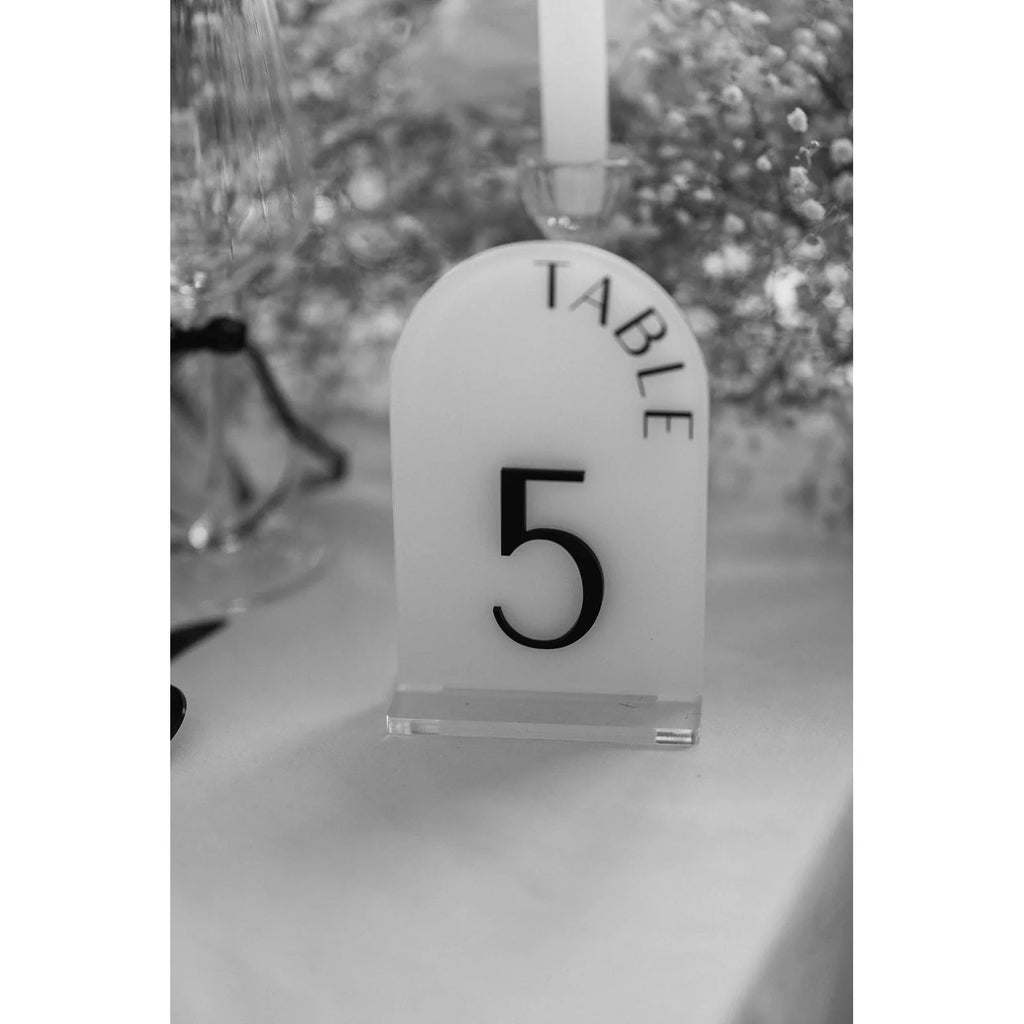 Tischnummer 6 aus Acrylglas zwischen Kerzenlicht und weißen Hortensien auf dem Hochzeitstisch.