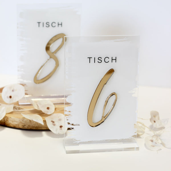 Zwei rechteckige Tischnummern aus Acryl mit goldenen 3D-Zahlen 8 und 6 auf Holztablett mit getrockneten Blüten.